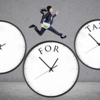 Tax Day Is April 18th This Year concept of time for taxes with a businesswoman running on watch