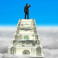 businessman reaching the top of money stairs