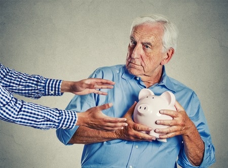 senior man clutching piggy bank