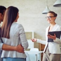 female broker consulting young couple in realtor office