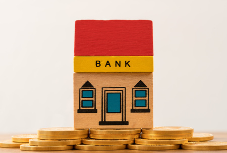toy brick bank building sitting on solid gold assets as illustration of too big to fail banks. repeal of dodd-frank could jeopardize the assets of large investment banks