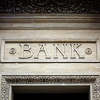 old bank sign engraved in stone or concrete above the door of financial building concept for finance and business