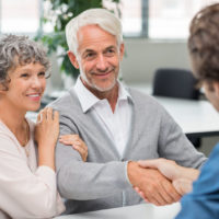 happy senior couple shaking hands with retirement consultant. smiling senior man shaking hands with young businessman for business agreement. handshake between senior man and financial agent after obtaining a loan.