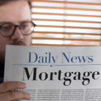 man reading mortgage headlined newspaper