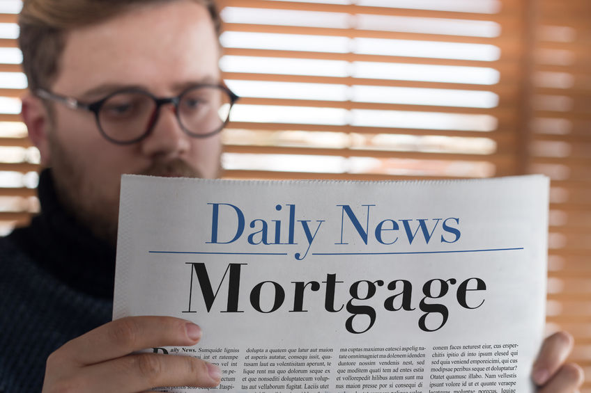 man reading mortgage headlined newspaper