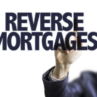 business man pointing to transparent board with text: reverse mortgages