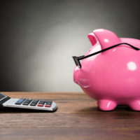 piggybank with eyeglasses and calculator on wooden table