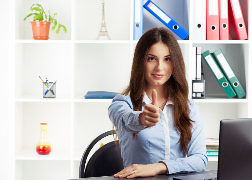 young successful female real estate specialist showing thumb up. concept of success in business. smiling woman specialist sitting at the desk in the office.