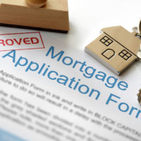 Approved Mortgage loan application with house key and rubber stamp