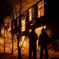 Photo of Firemans Trying to Safe House on Fire. Firefighter Emergency Extinguish Water on Big Old Wooden House on Fire