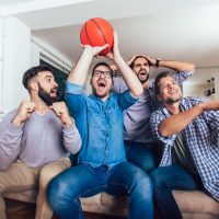 Happy friends or basketball fans watching basketball game on tv and celebrating victory at home.Friendship, sports and entertainment concept.