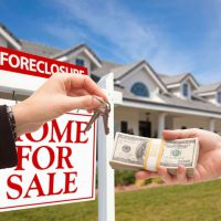 42908957 - handing over cash for house keys in front of house and foreclosure sign